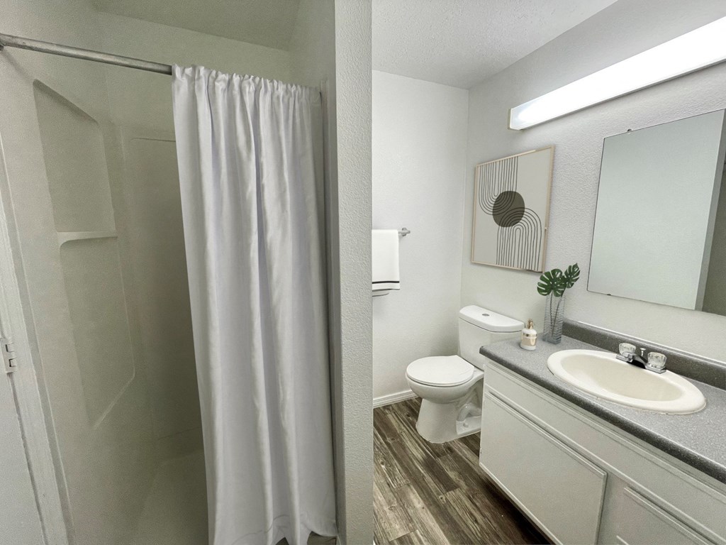 A bathroom with a white shower curtain and a white toilet.